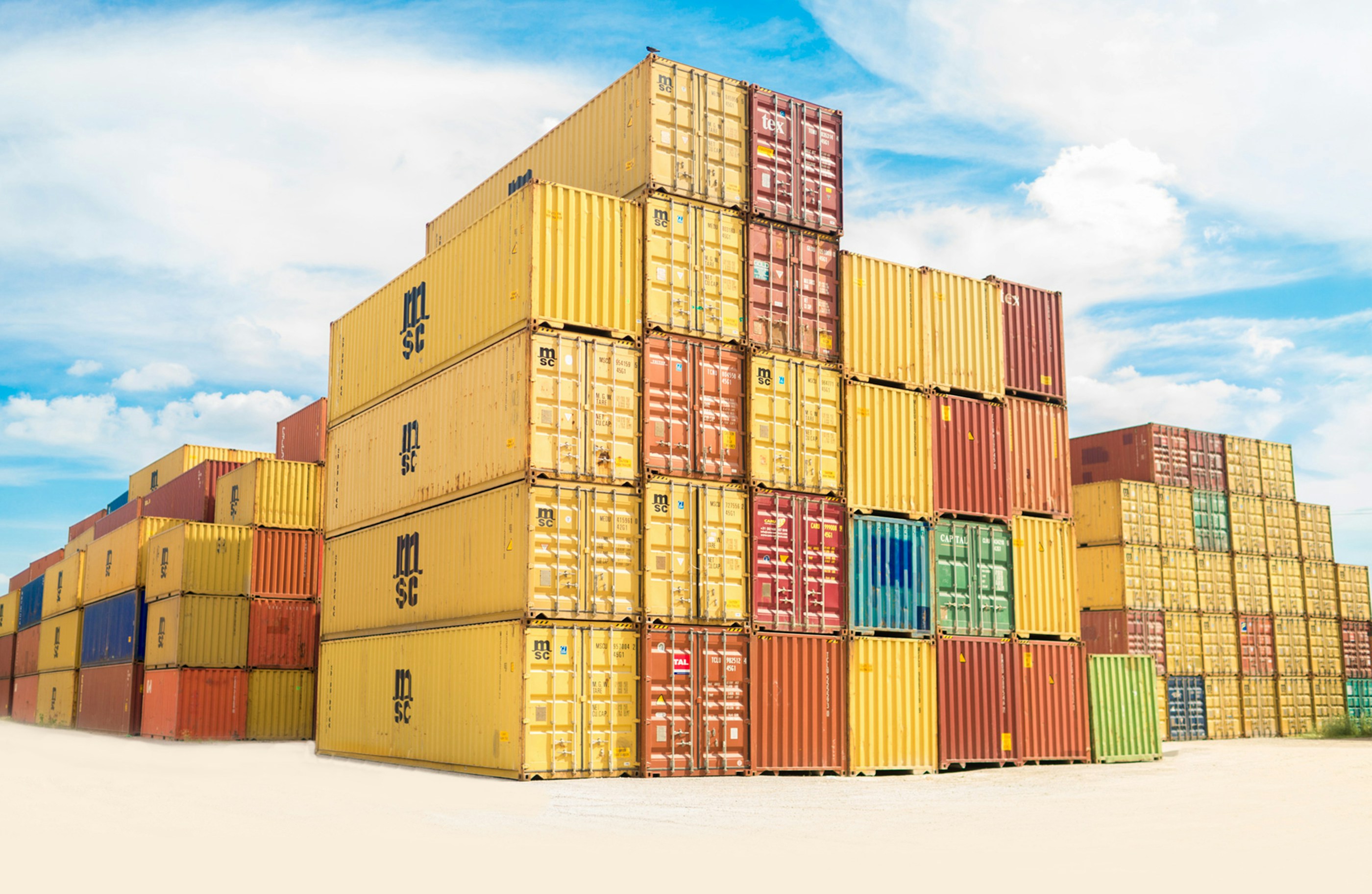 Hoch gestapelte, bunte Frachtcontainer unter blauem Himmel